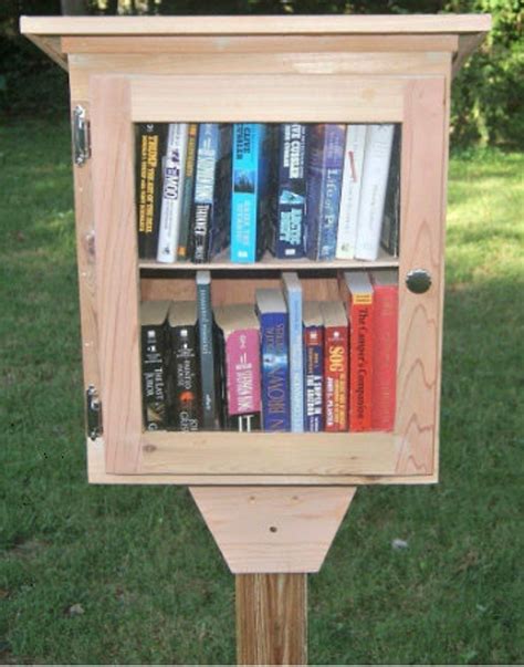 A wooden box filled with books, visible from a acrylic cut-out: a community library box.